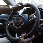 Close-up of a man's hands on a luxury car steering wheel highlighting modern interior.