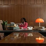 African American woman typing on an antique typewriter in a vintage office setting.