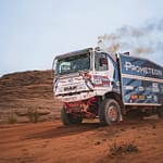A rugged off-road racing truck powers through a desert terrain, showcasing speed and endurance.